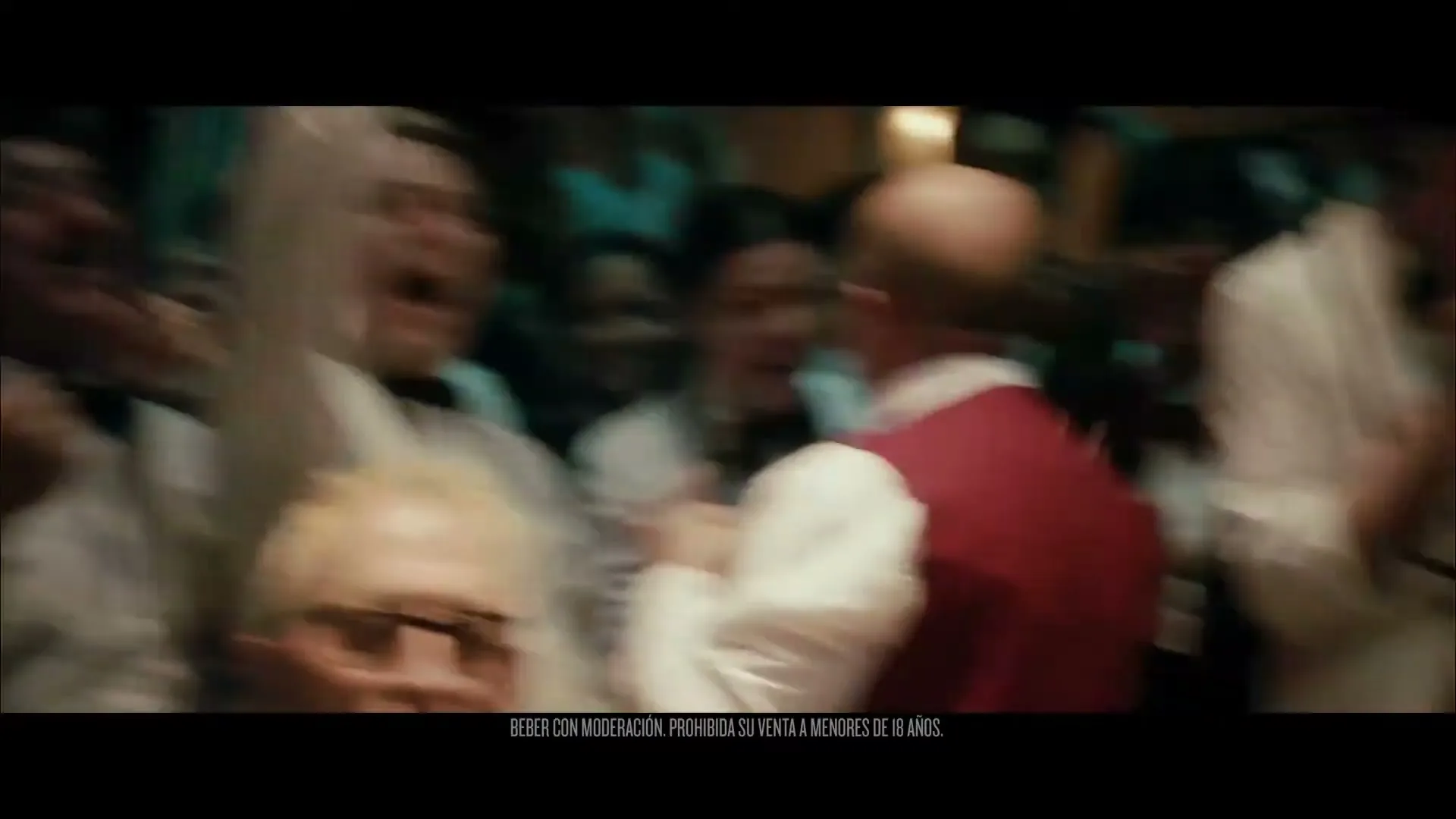 A diverse group of waiters and waitresses, dressed in white shirts and bow ties, cheer excitedly in a lively, dimly lit restaurant.