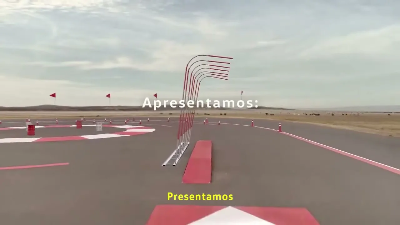 A wide shot of an empty outdoor test track with red and white markings, under a cloudy sky, with text overlay.