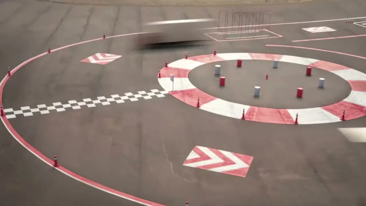 An aerial view shows a truck speeding through a test track with red and white markings and cones, demonstrating its agility.