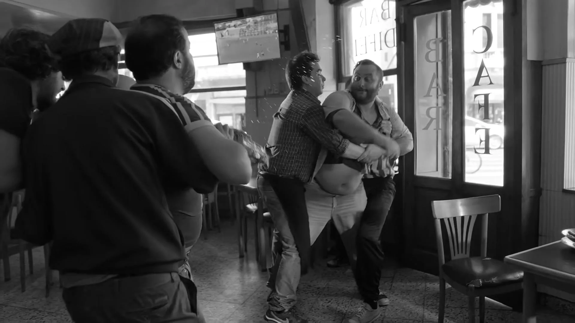Two men in a bar fight, one with a large belly, are being held back by other men in a busy, old-fashioned bar.