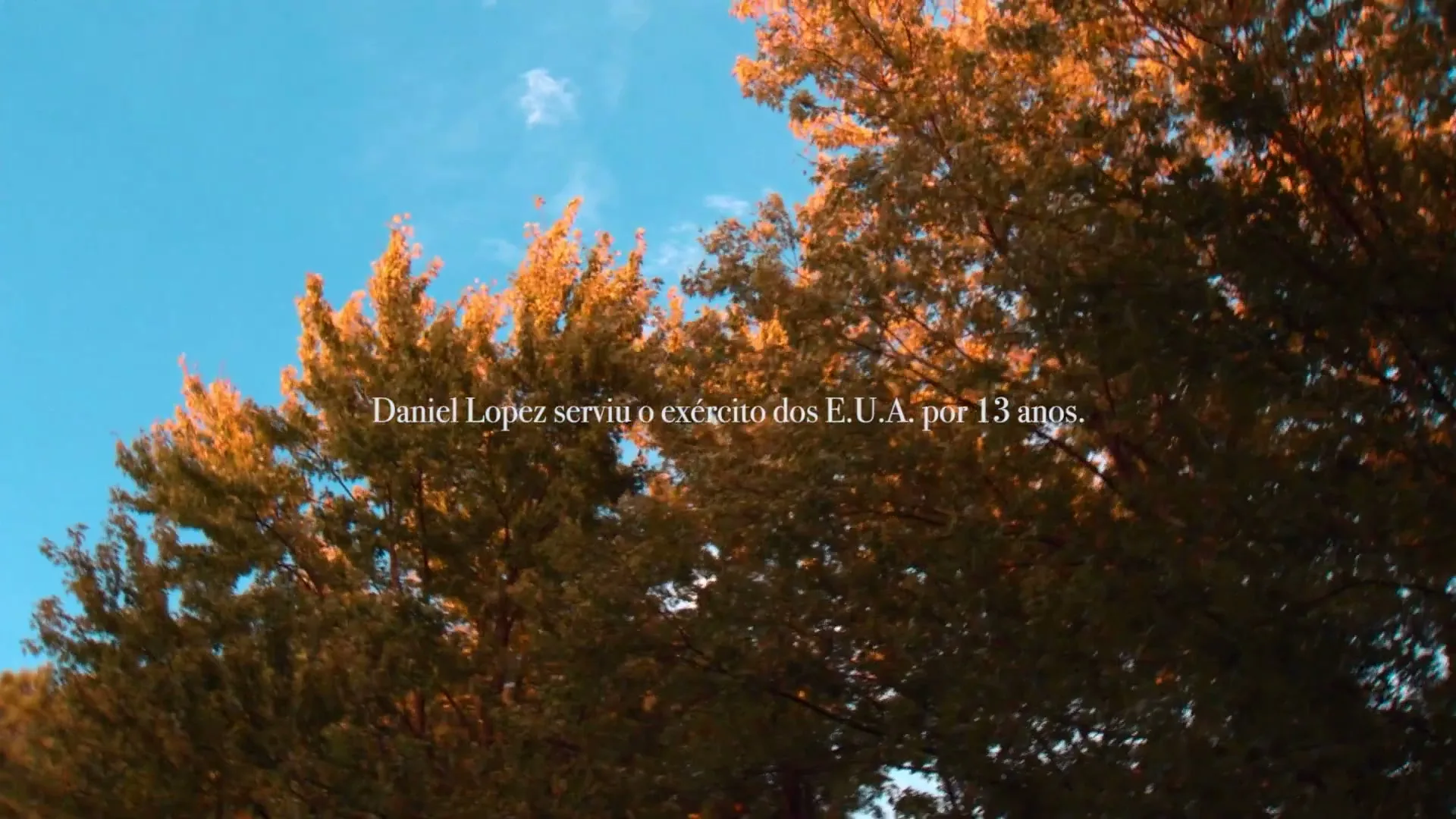 A low-angle shot of trees with golden leaves against a bright blue sky, with text overlay about Daniel Lopez's military service.