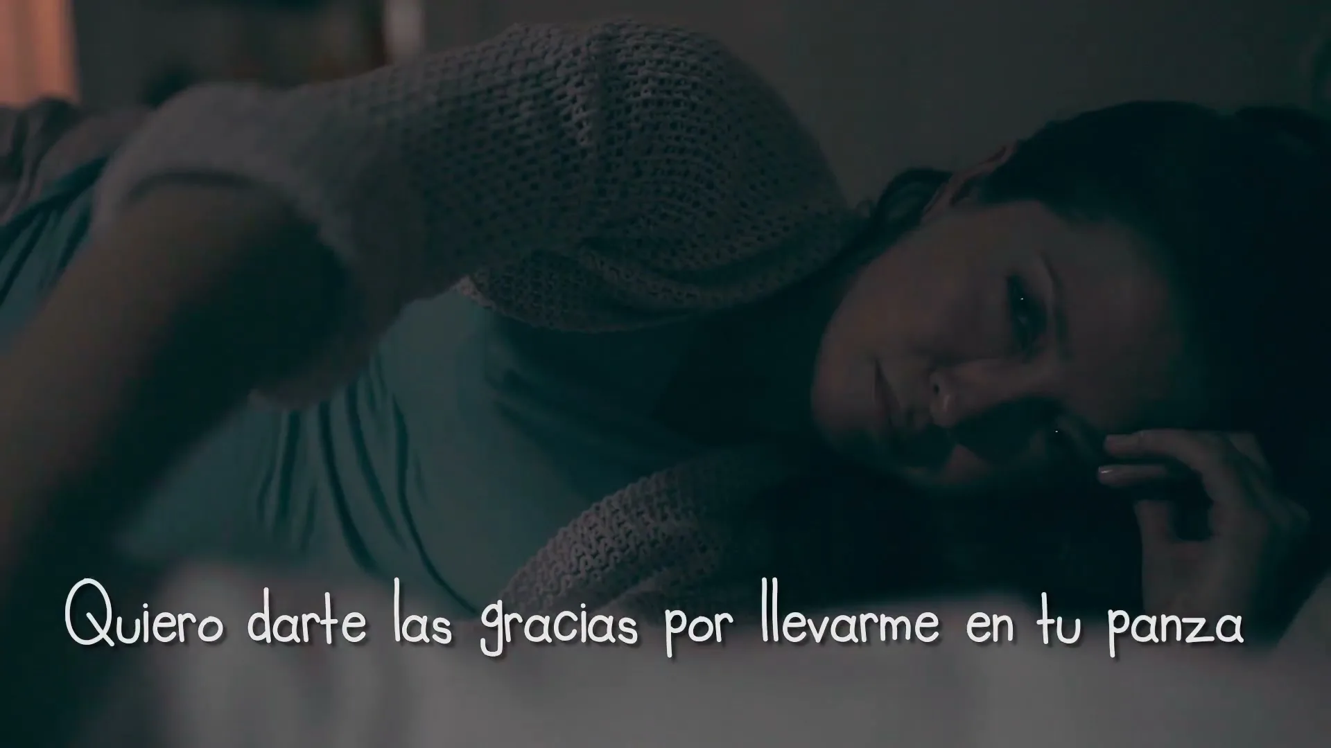 A pregnant woman lies in bed, looking tired and emotional, with on-screen text appearing as she speaks in a dark bedroom.