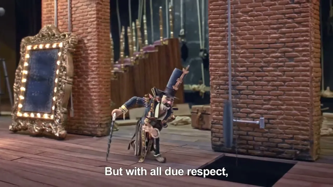 A stop-motion puppet, dressed in a black and gold ringmaster costume, stands on a wooden stage next to a lit mirror, then is pulled up by a rope.
