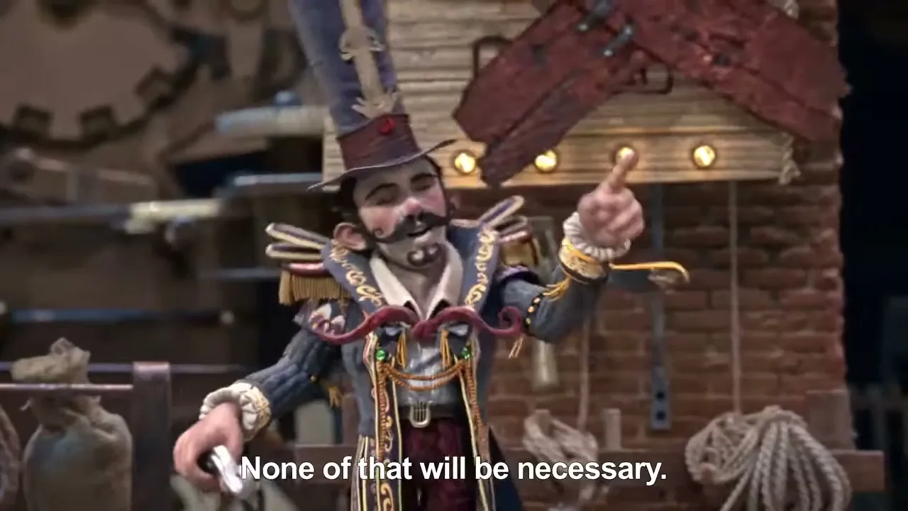 A male puppet with a top hat and elaborate costume gestures with his hands, then points his finger up, in a factory-like setting.