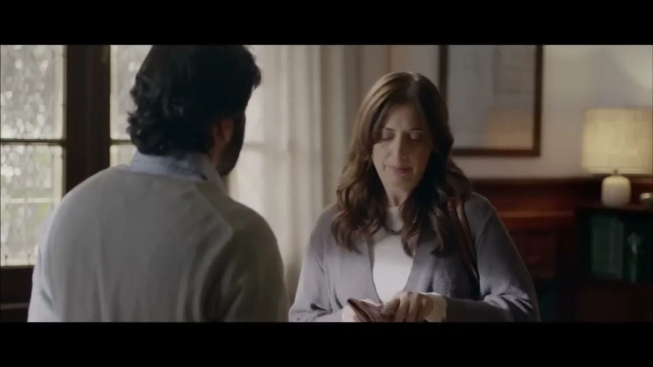 A woman in her 40s, wearing a grey cardigan, looks at a man from behind in a therapist's office.