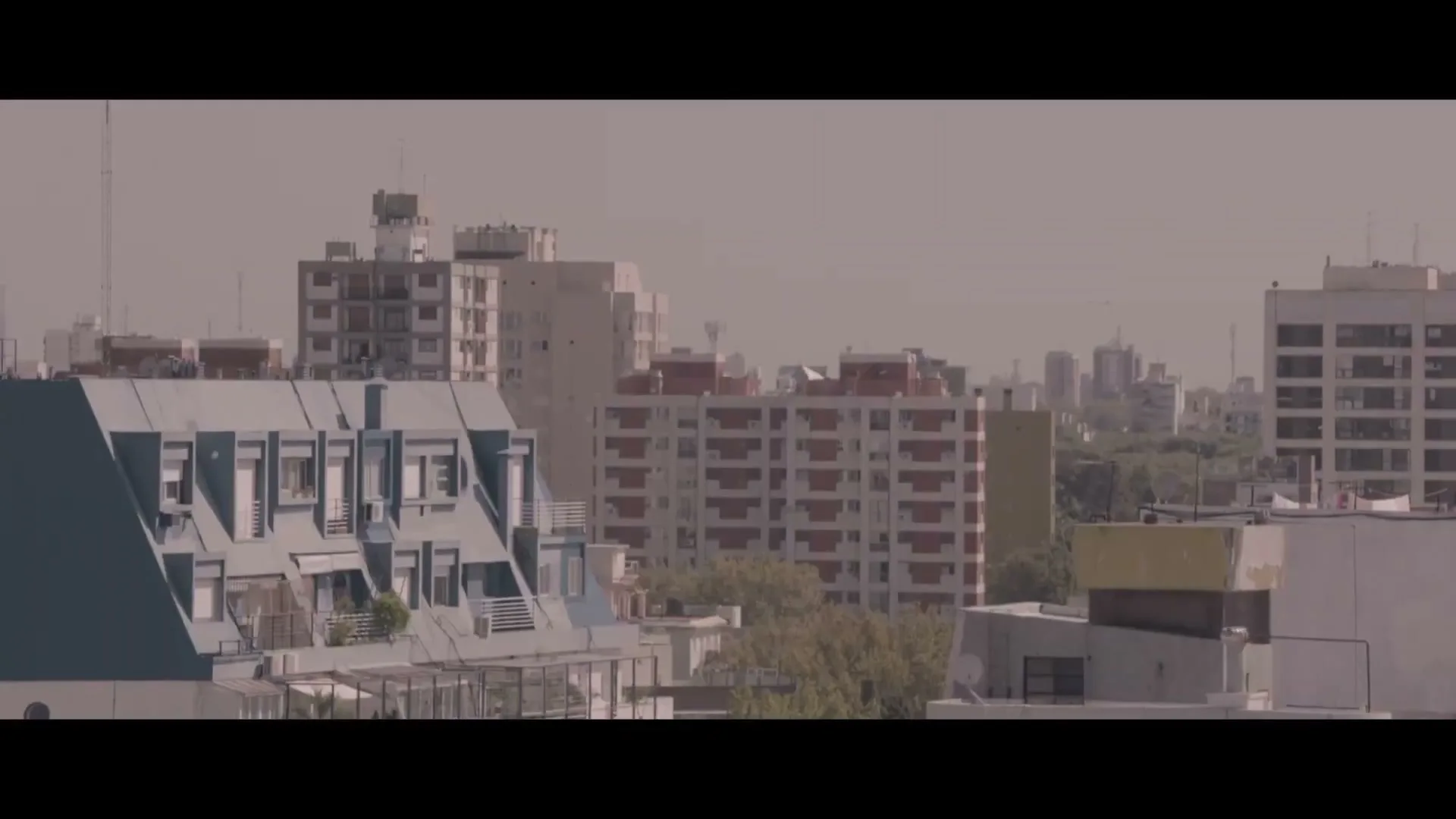 A wide shot of a city skyline with various buildings under a hazy sky, showcasing urban architecture.