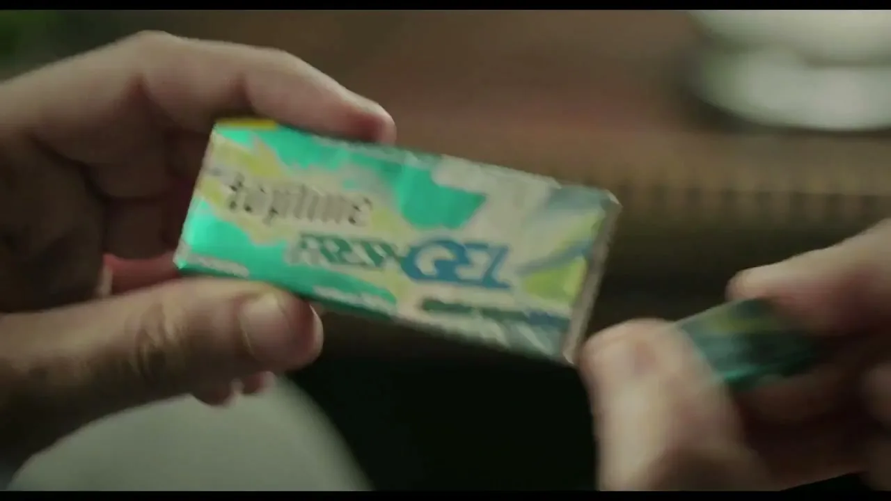 A person's hands hold a pack of Topline Fresh Gel gum, opening it to reveal a piece inside, in a close-up shot.