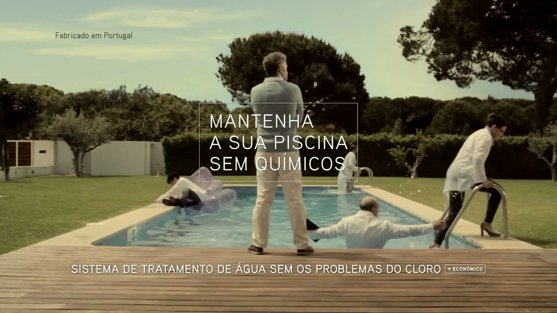 A man stands with his back to the camera, looking at several scientists in lab coats in and around a swimming pool in a backyard.