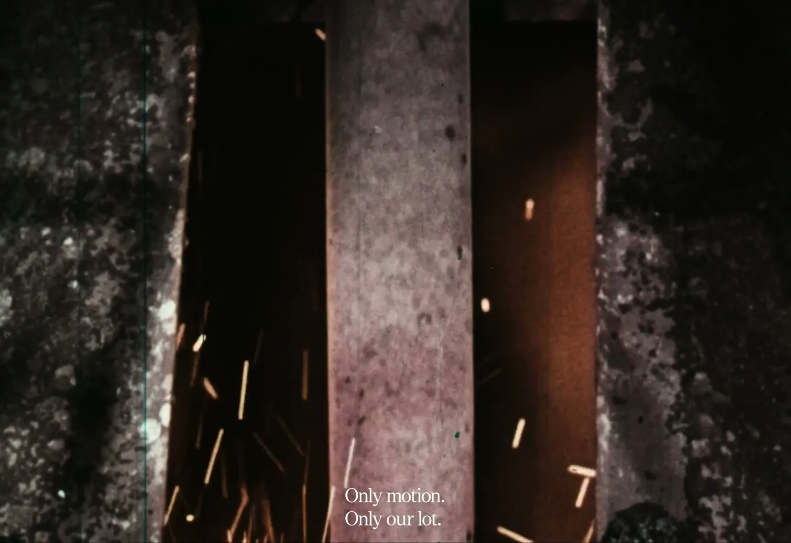 Sparks fly upwards between two dark, textured walls and a central concrete pillar, with text at the bottom of the frame.