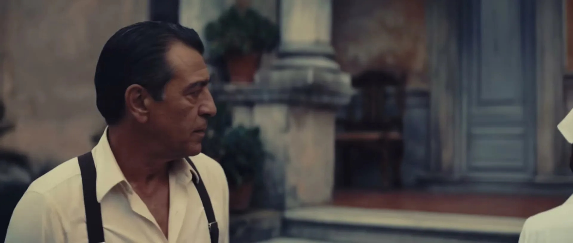A man in a white shirt and suspenders talks to a nurse in a white uniform, then they both turn and walk into a building.