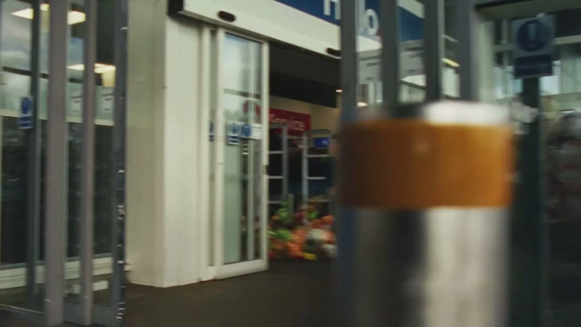 A young boy in a blue sweater runs through a supermarket, with fruits and vegetables falling around him, then runs out the automatic doors.
