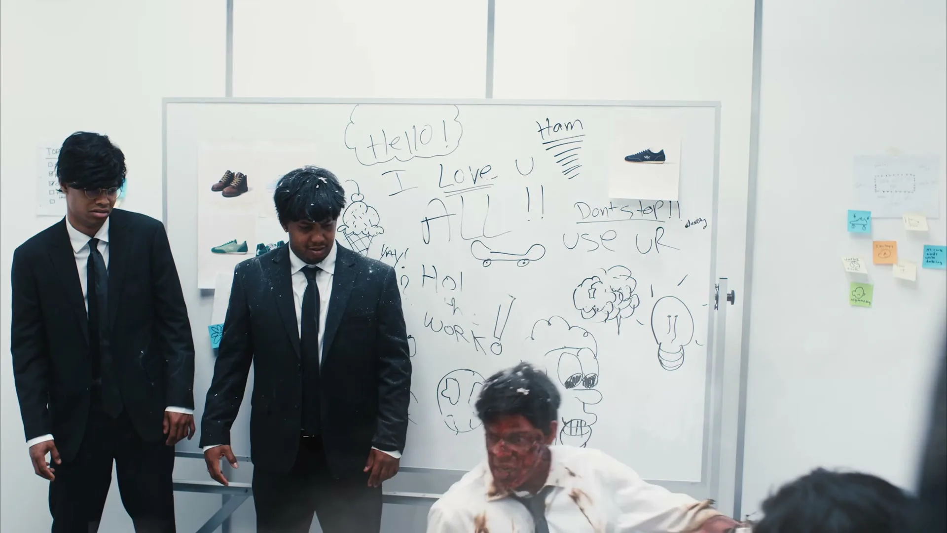 Three men in suits are in an office, two standing and one on the floor, who holds a glowing object in his hand.