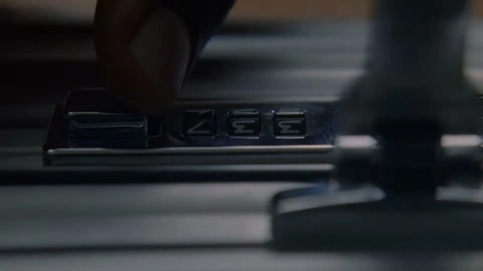 A person's finger adjusts the combination lock on a silver suitcase, setting the numbers to '733'.