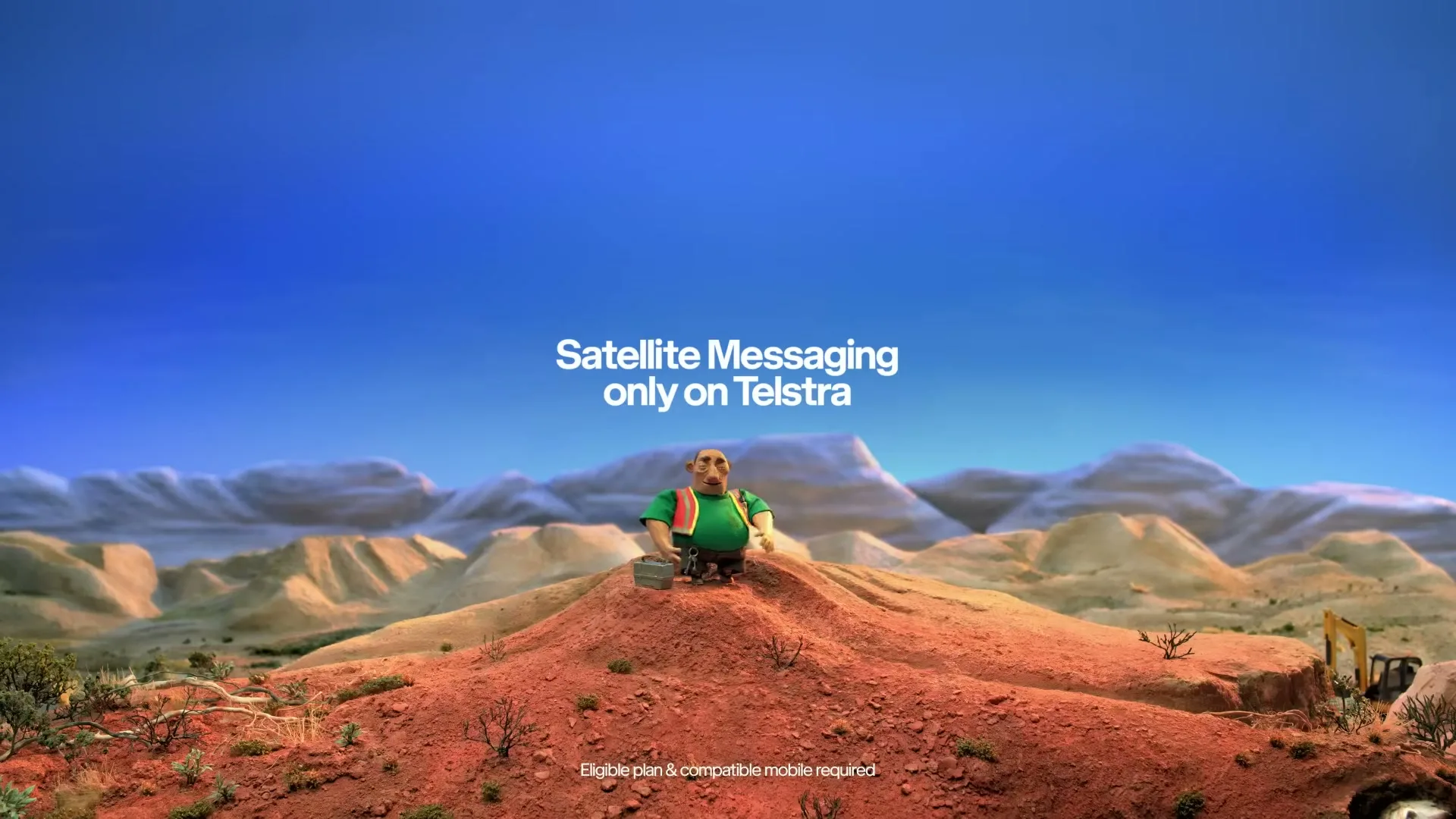 A claymation man in a green shirt and brown pants sits on a red dirt mound in a desert landscape, looking around, with text appearing on screen.
