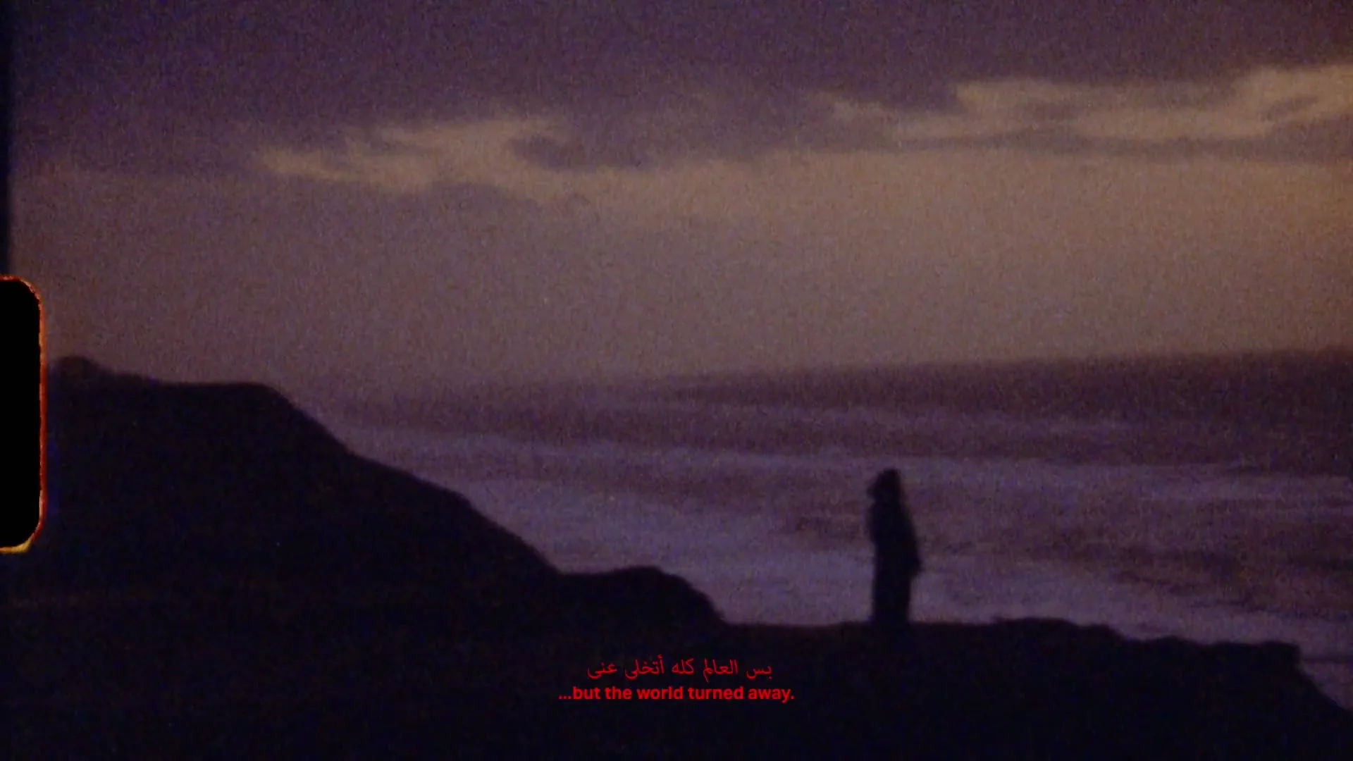 A lone figure stands silhouetted against a dramatic ocean backdrop at dusk, with red text overlaid on the scene.