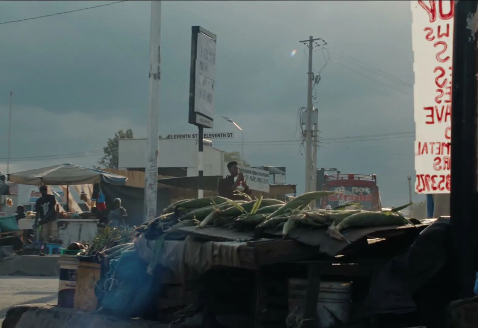 A busy street market scene with people walking, a bus, and a stall piled with corn, as a text message from "Gran" asking "Where are you???" appears on screen.