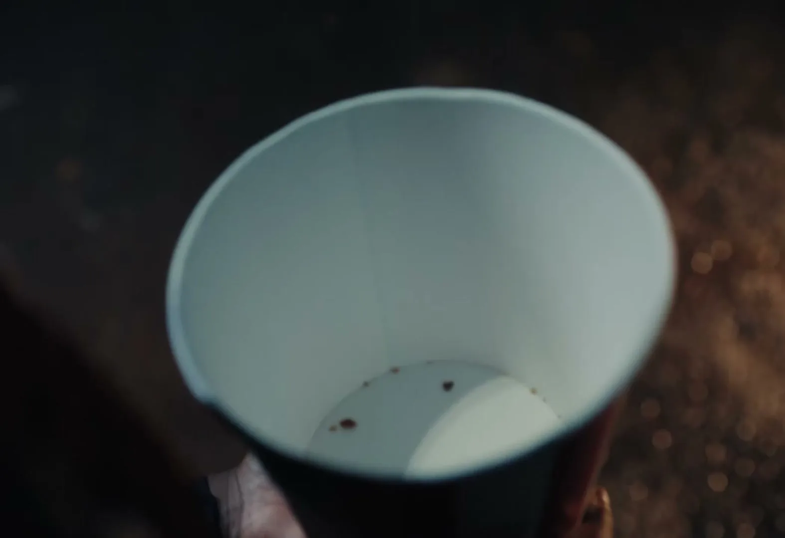 A person holds an empty KFC bucket with a few crumbs at the bottom, looking down into it.