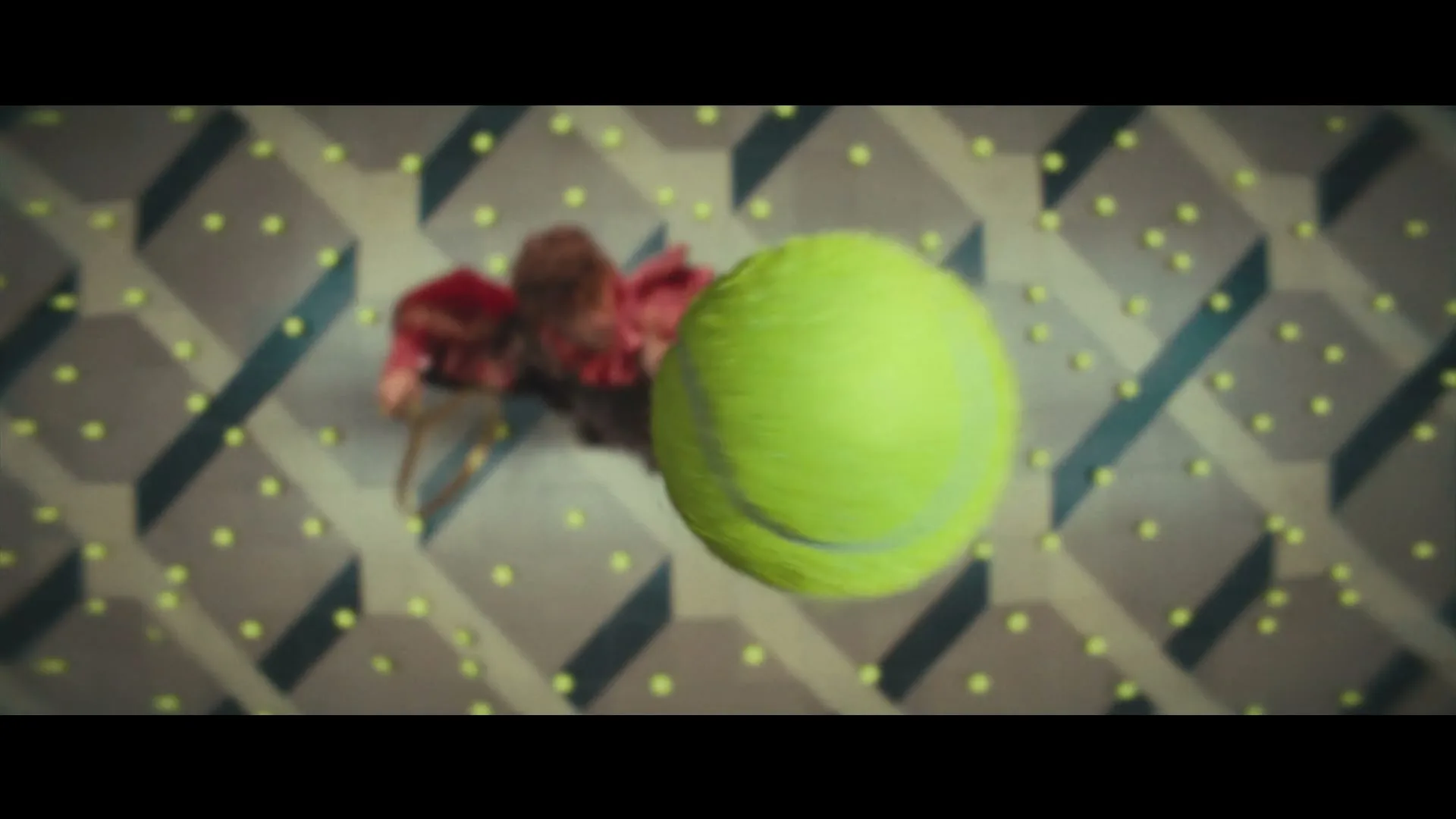 A woman in a red dress with a tennis racket serves a tennis ball on a patterned floor covered in tennis balls.