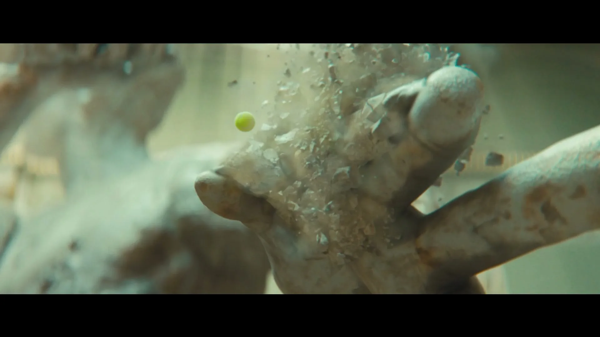 A tennis ball hits a stone statue's hand, causing it to shatter into pieces, in a bright, outdoor setting.