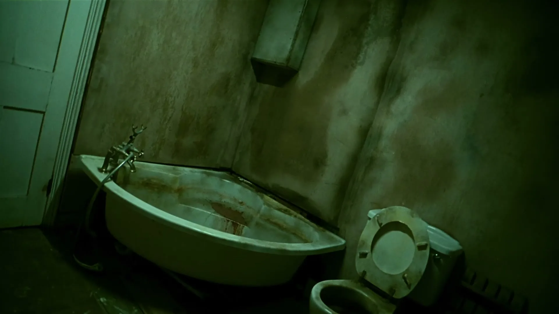 A dirty, dilapidated bathroom with a grimy bathtub and toilet is shown in a dark, unsettling green light.