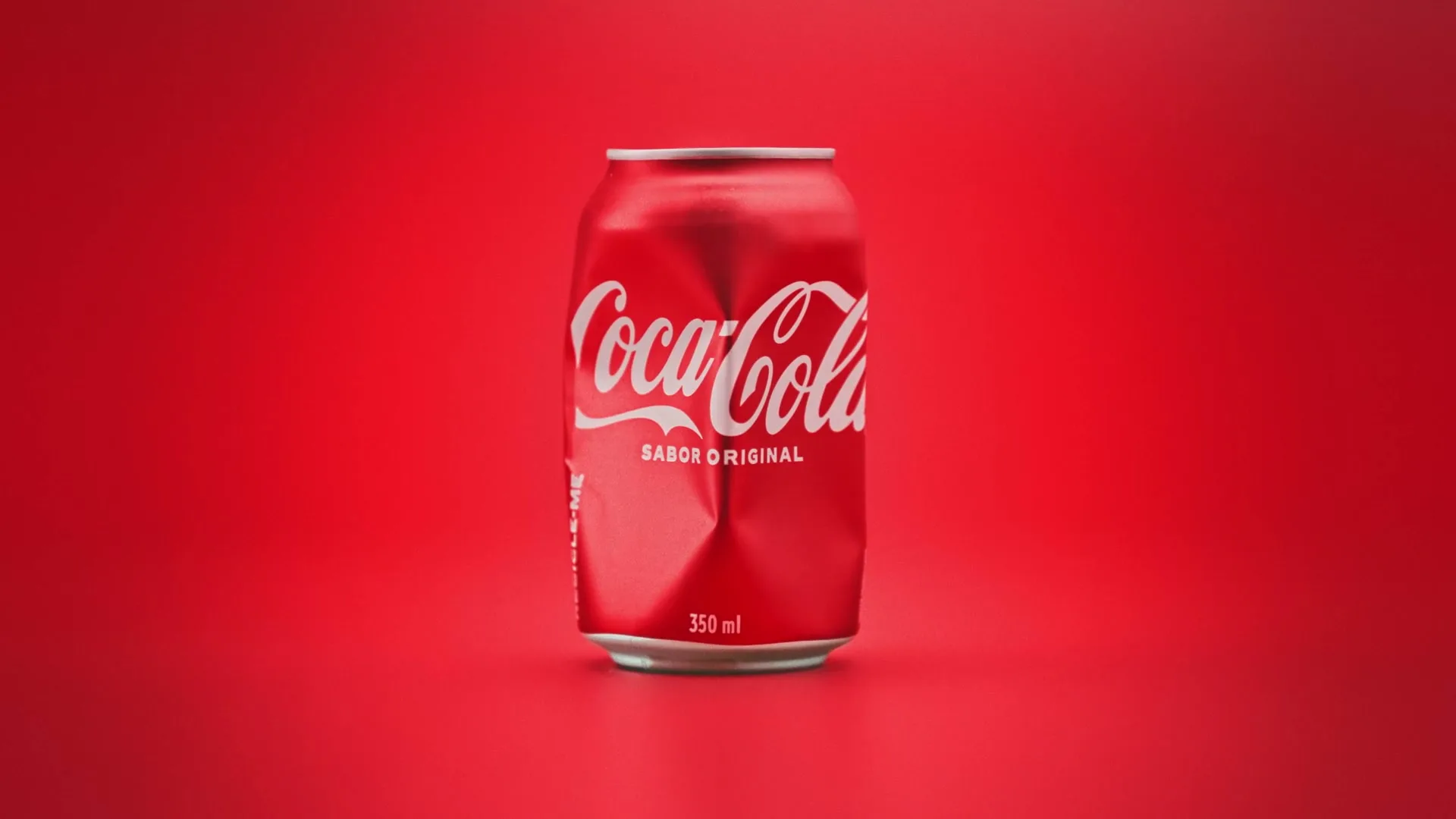 A red Coca-Cola can, initially pristine, slowly crumples and deforms against a vibrant red background, accompanied by a melancholic song.