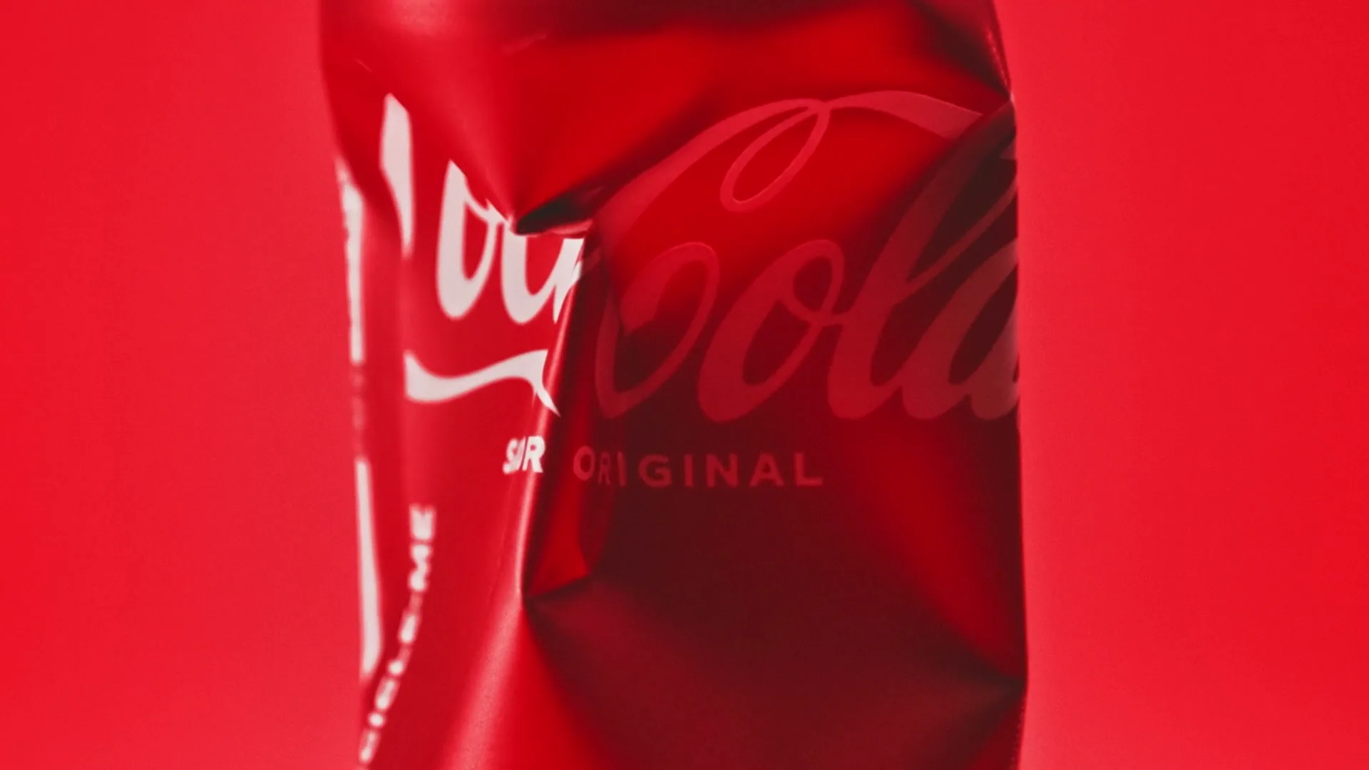 A crumpled red Coca-Cola can with white lettering is shown against a red background.