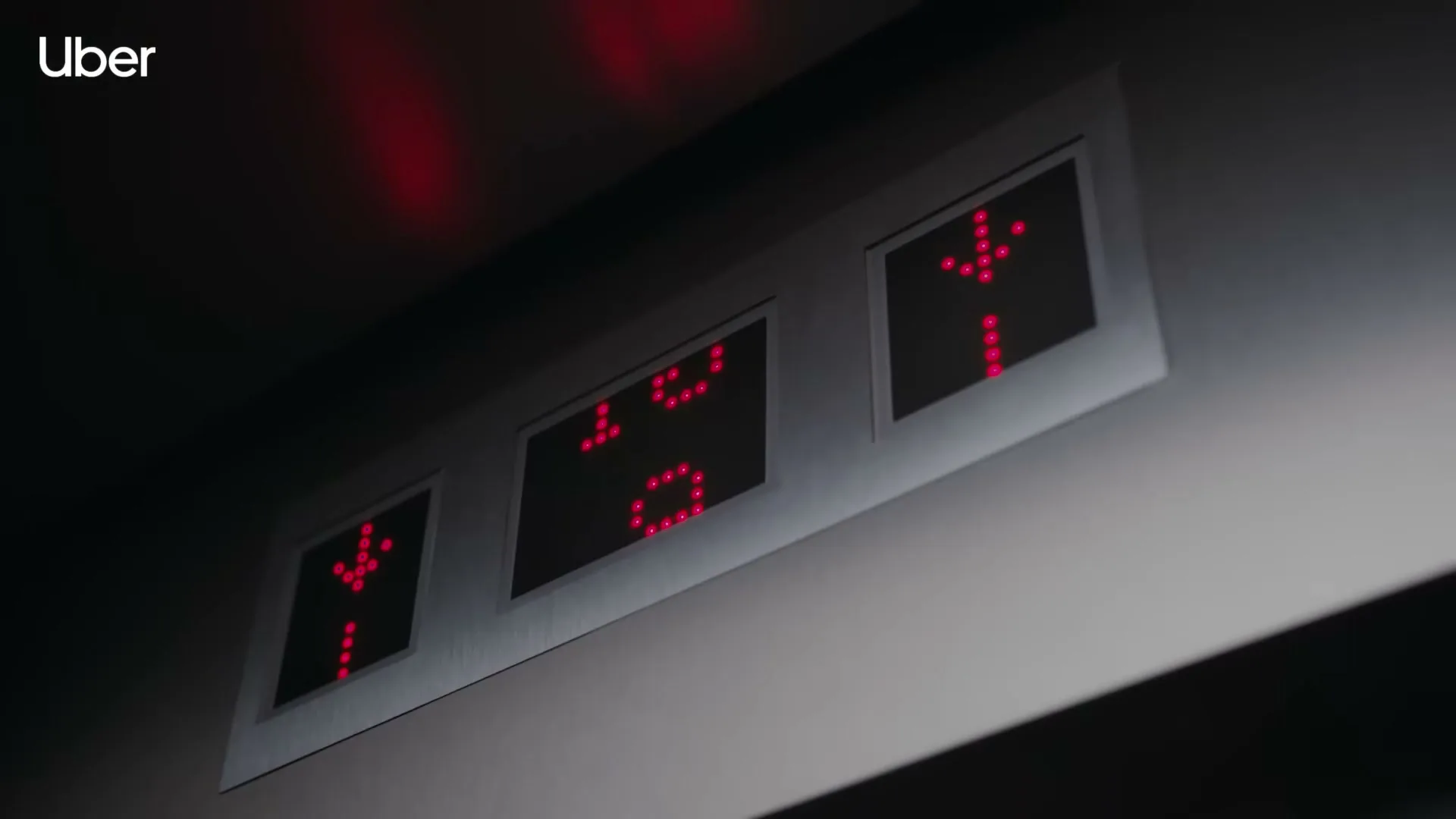 A close-up shot of an elevator panel shows the floor number decreasing from 10 to 9, with red arrows indicating downward movement.