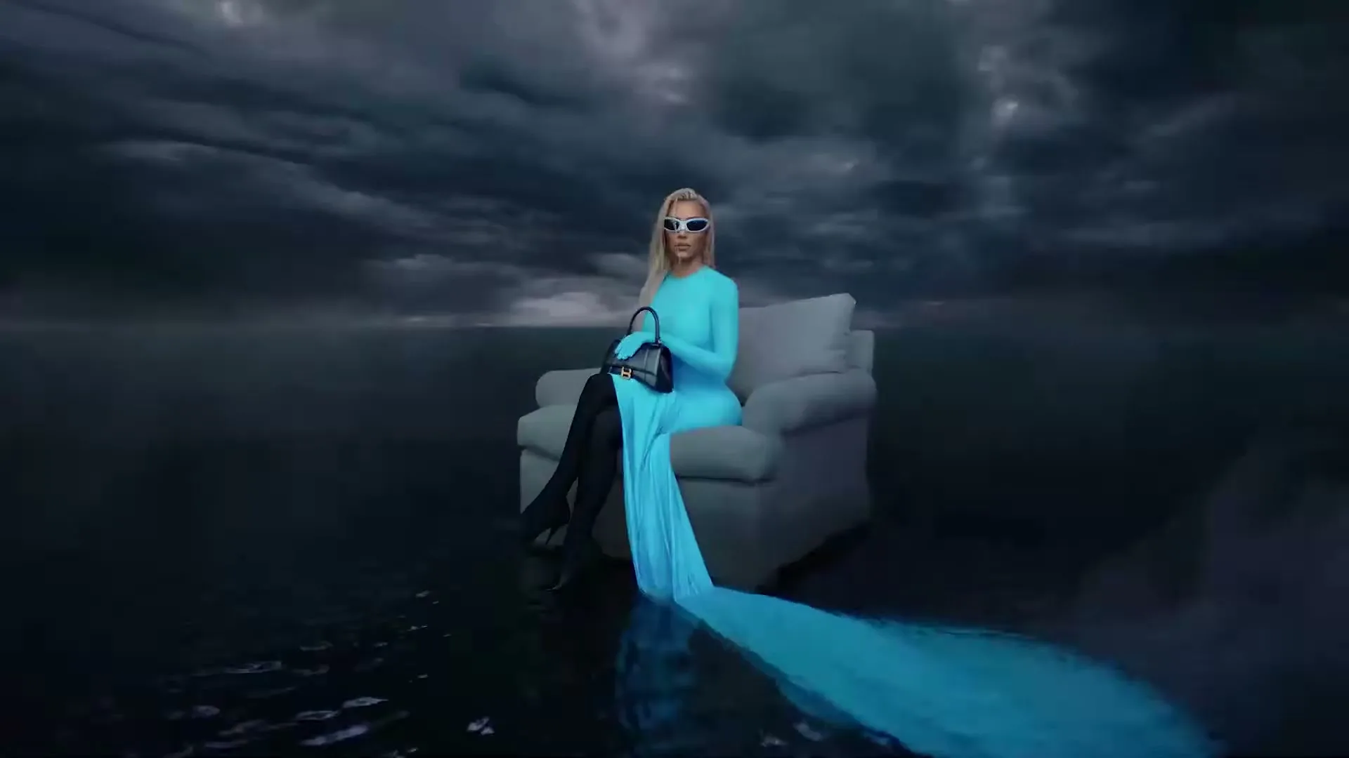 A blonde woman in a long blue dress and sunglasses sits on a couch in a flooded, stormy landscape, holding a black handbag.