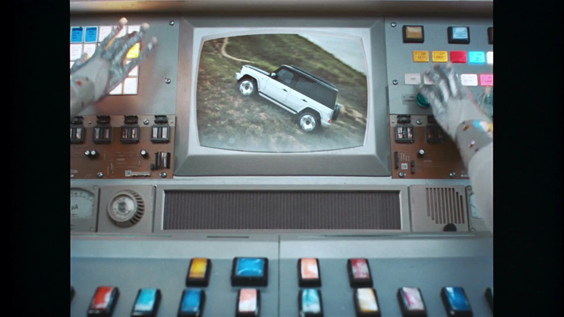 A pair of robotic hands with paint splatters operate a retro control panel, featuring a monitor displaying a white SUV on a dirt road and the word "ELECTRIC" on a digital display.