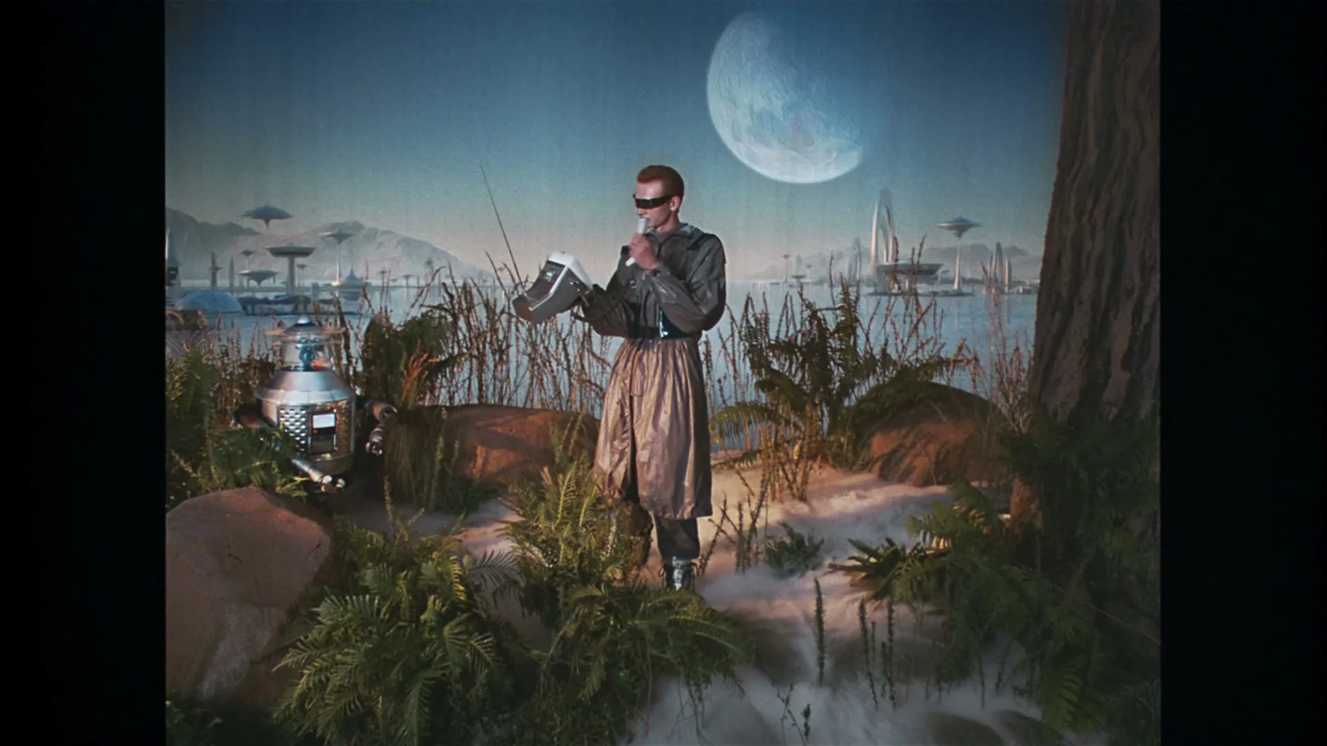 A person with red hair and futuristic glasses stands in a swampy landscape, holding a device, with a large moon and futuristic city in the background.