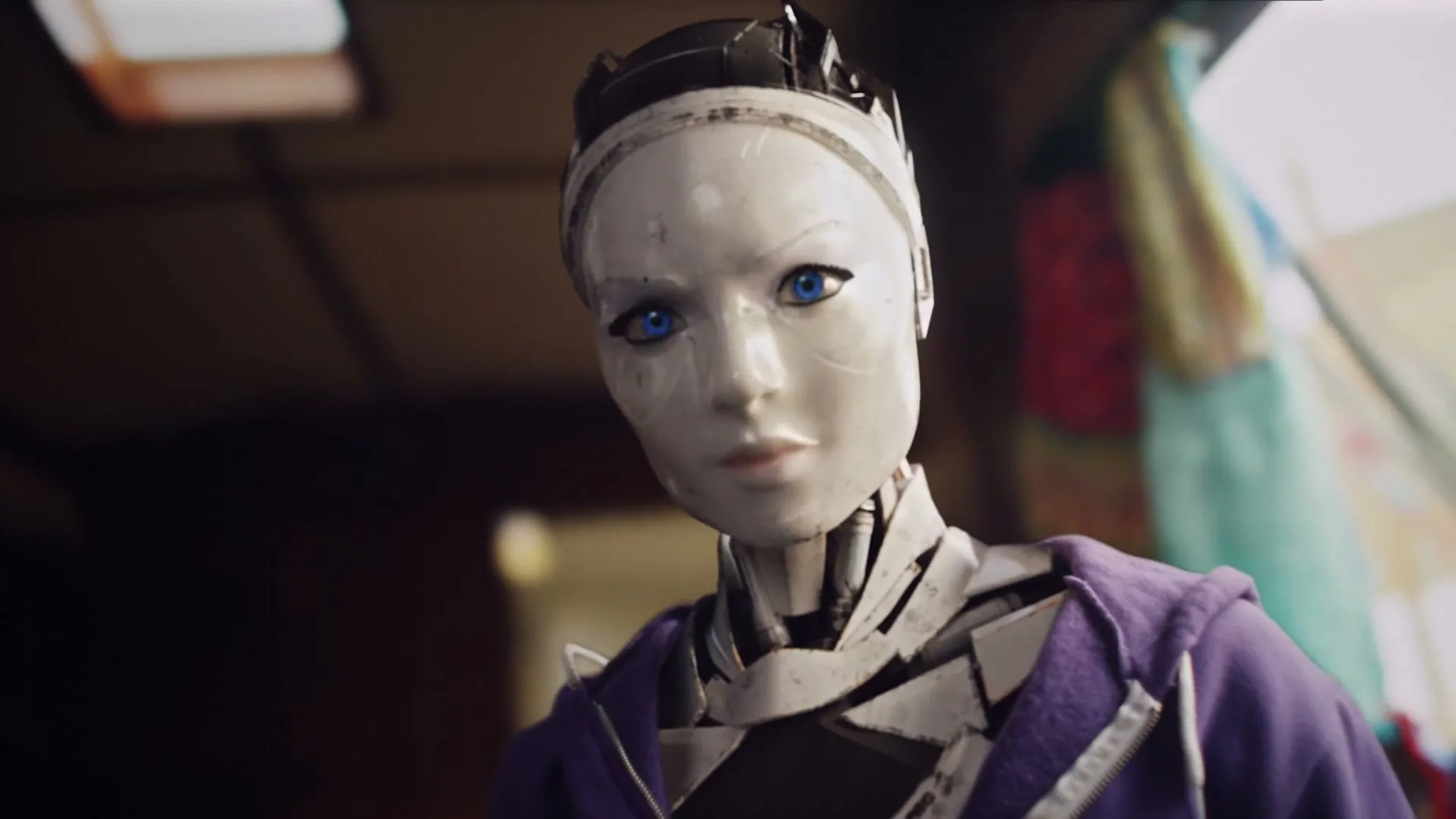 A female-presenting robot with a white face and blue eyes looks up, wearing a purple hoodie in an interior setting.