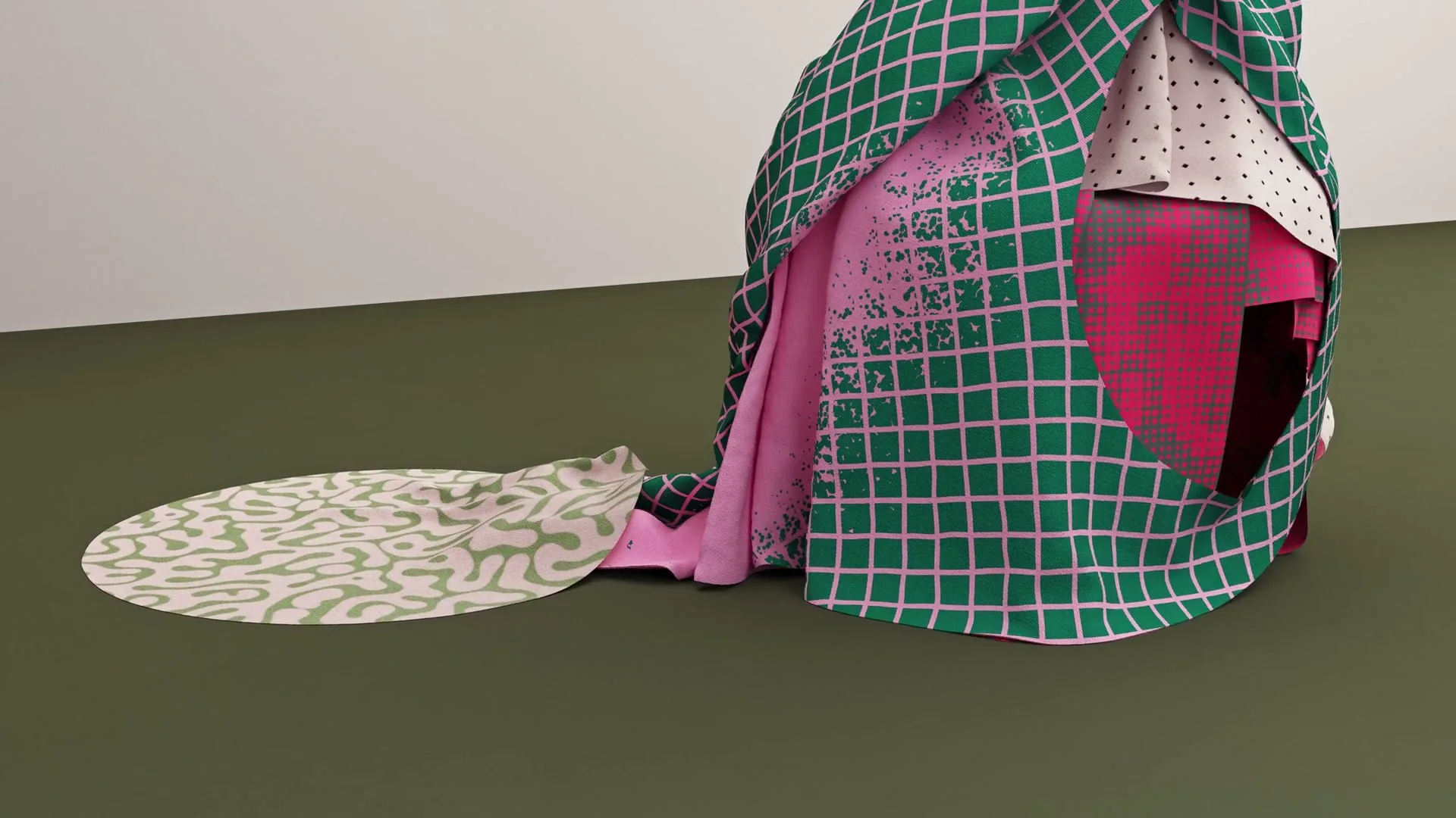 A colorful, patterned fabric sculpture with green, pink, and white patterns sits on a dark green floor against a light gray wall.