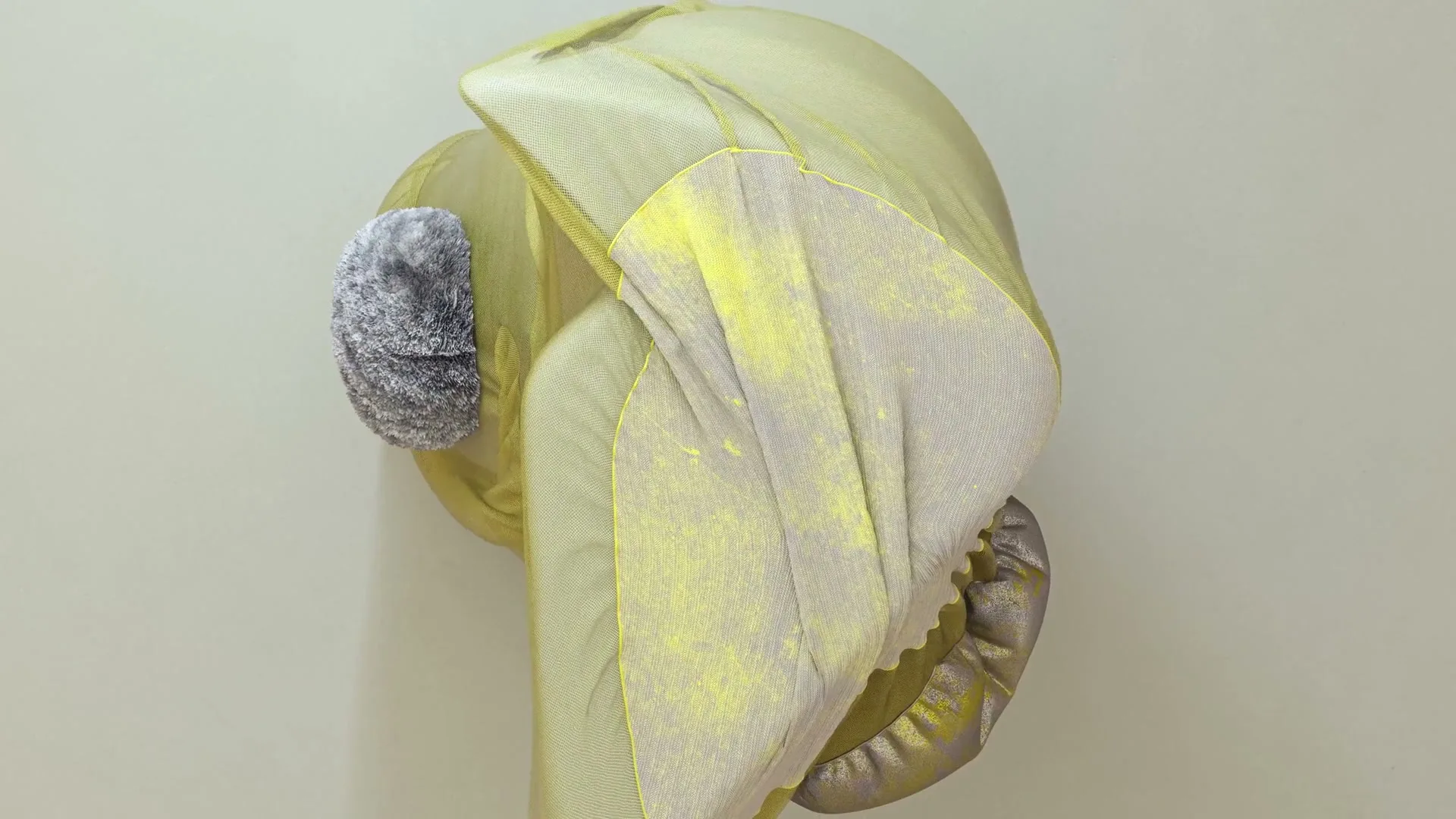 A yellow and grey abstract, organic shape with a textured surface rotates slowly against a plain background.