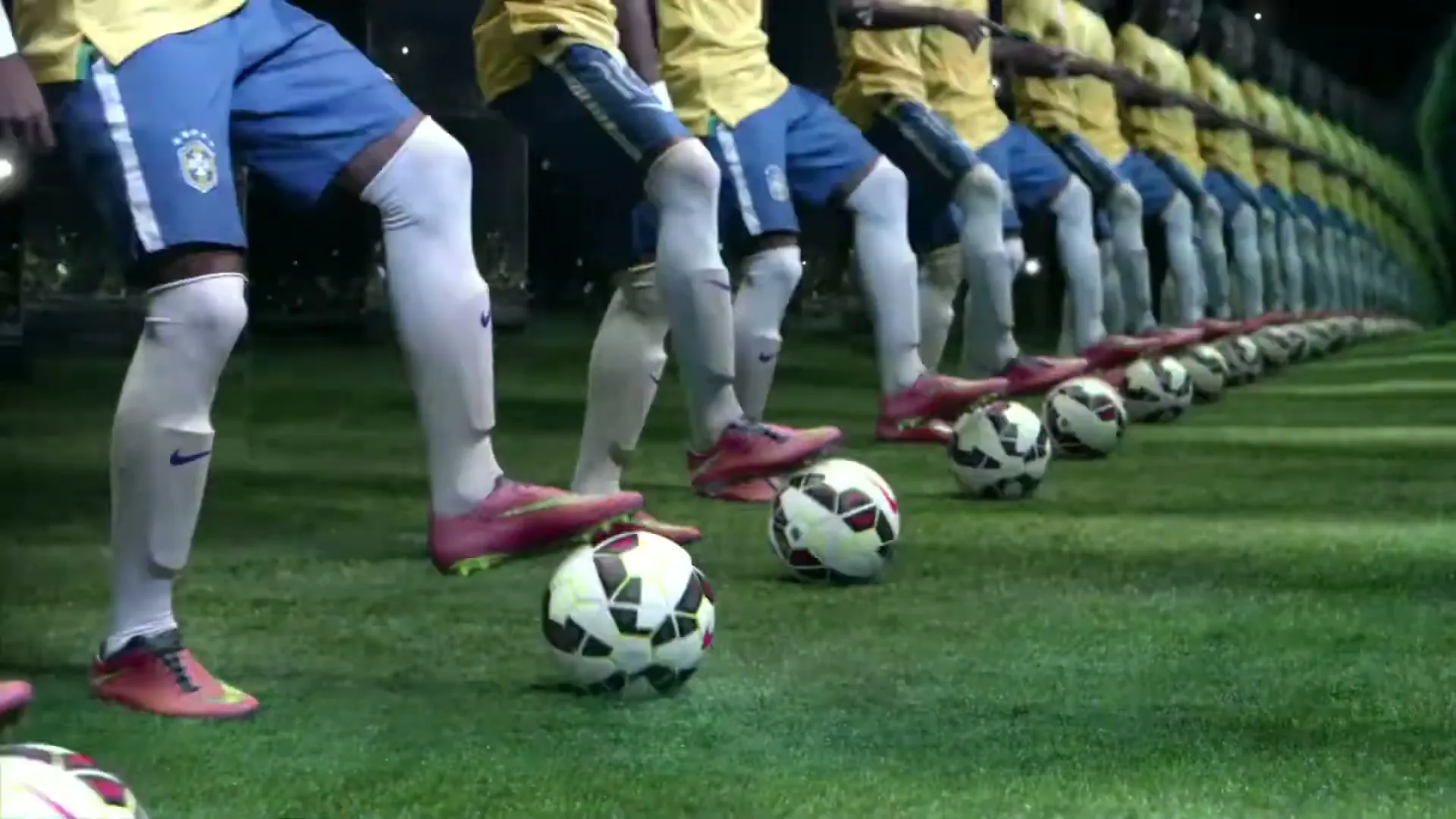 A soccer player in a yellow jersey and blue shorts juggles a soccer ball, with many mirrored versions of himself stretching into the distance on a green field at night.