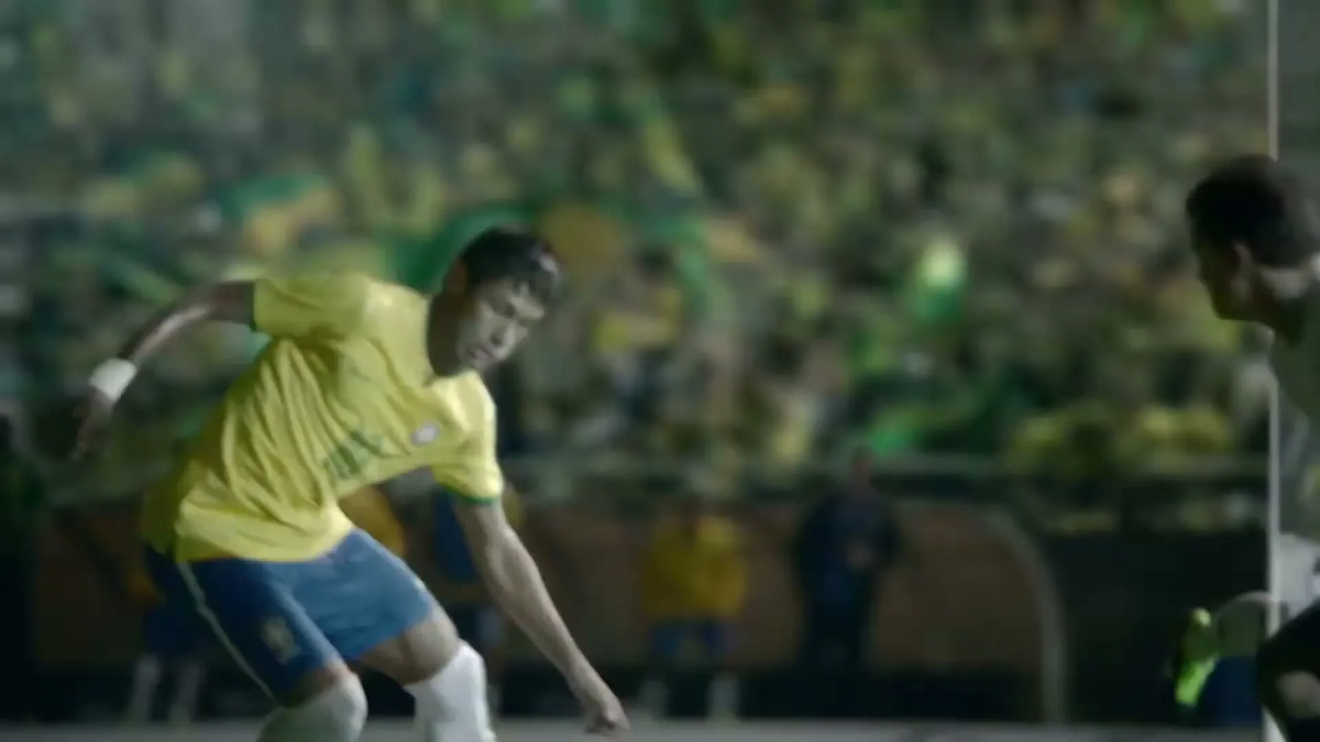 Neymar Jr. in a yellow and blue soccer uniform dribbles a soccer ball on a green field, with a stadium crowd in the background.