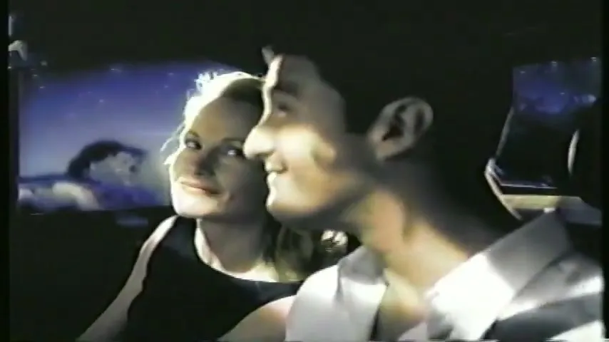 A man and woman in a car look up at the night sky, which is visible through the sunroof.