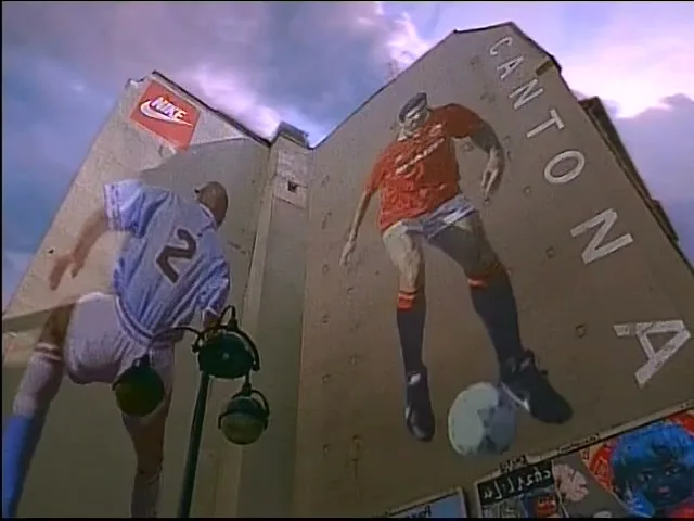 A low-angle shot of a building with a large mural of two soccer players, one in a red jersey and one in a white jersey, with a Nike logo visible on the building.