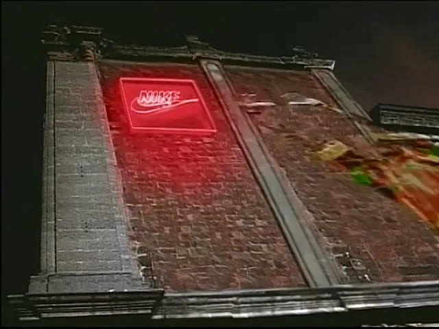 A red neon Nike logo sign is affixed to a brick wall at night, then a blue energy blast hits it.