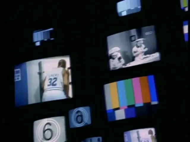 Multiple small screens display various video feeds, including a basketball player, a black and white scene, and a color bar test pattern, against a dark background.