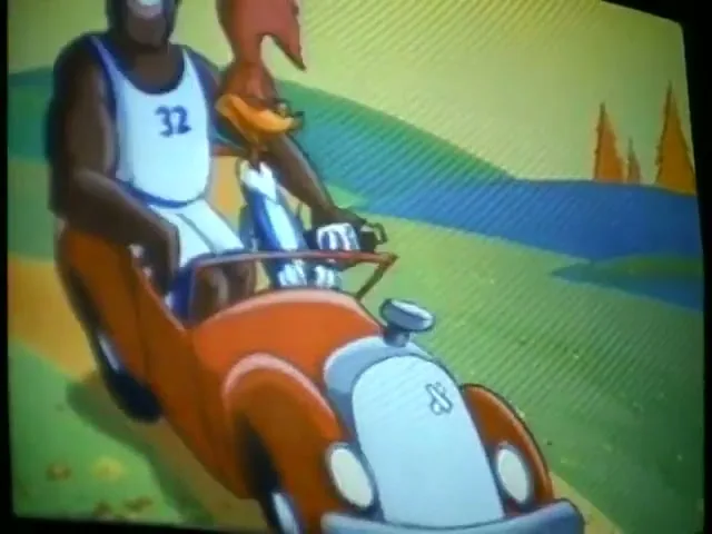 An animated Shaquille O'Neal and Woody Woodpecker drive a red vintage car down a winding road in a cartoon landscape.