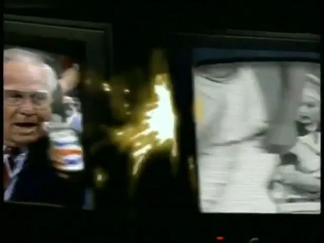 A split screen shows a black and white clip of a woman in a chef's hat and uniform, and a man in a suit with a headset talking.