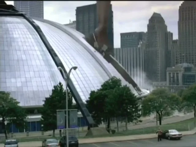 A giant foot wearing an Adidas shoe kicks a soccer ball, causing a stadium roof to collapse and water to spray, with a city skyline in the background.