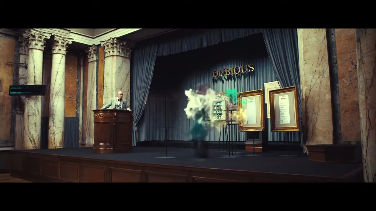 An auctioneer and a man in a suit stand on a stage, as a box with a question mark disappears in a puff of smoke.