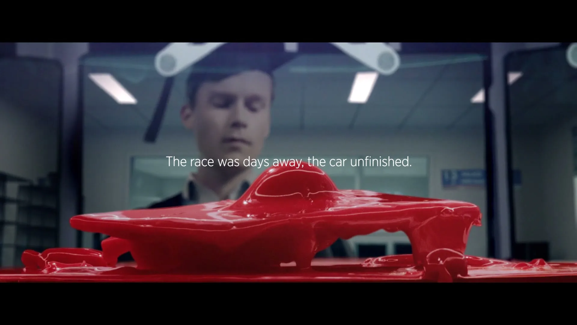 A young man in a graduation cap looks at a red liquid car model that melts and reforms, with text on screen.