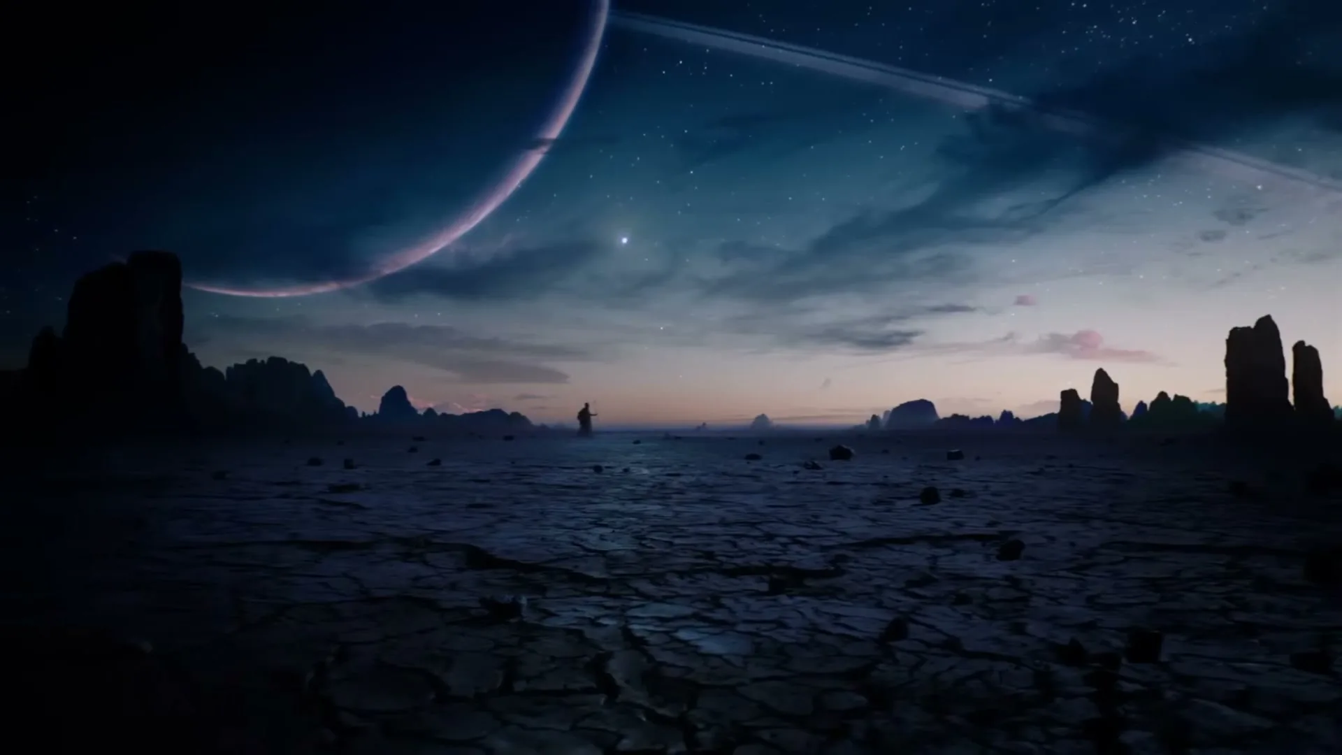 A lone figure stands on a cracked, barren alien landscape under a twilight sky with a ringed planet and stars visible.