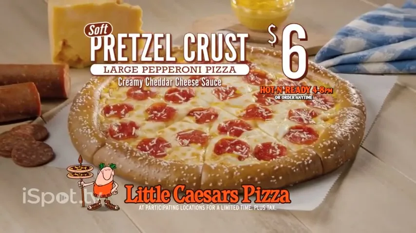 A delicious Little Caesars Soft Pretzel Crust Large Pepperoni Pizza with creamy cheddar cheese sauce is displayed on a wooden table with ingredients in a bright, inviting setting.