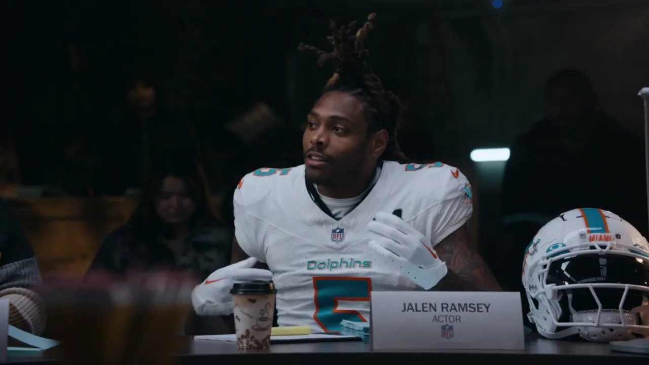 Jalen Ramsey, a male football player in a Miami Dolphins uniform, sits at a table during a table read, looking around with a confused expression.