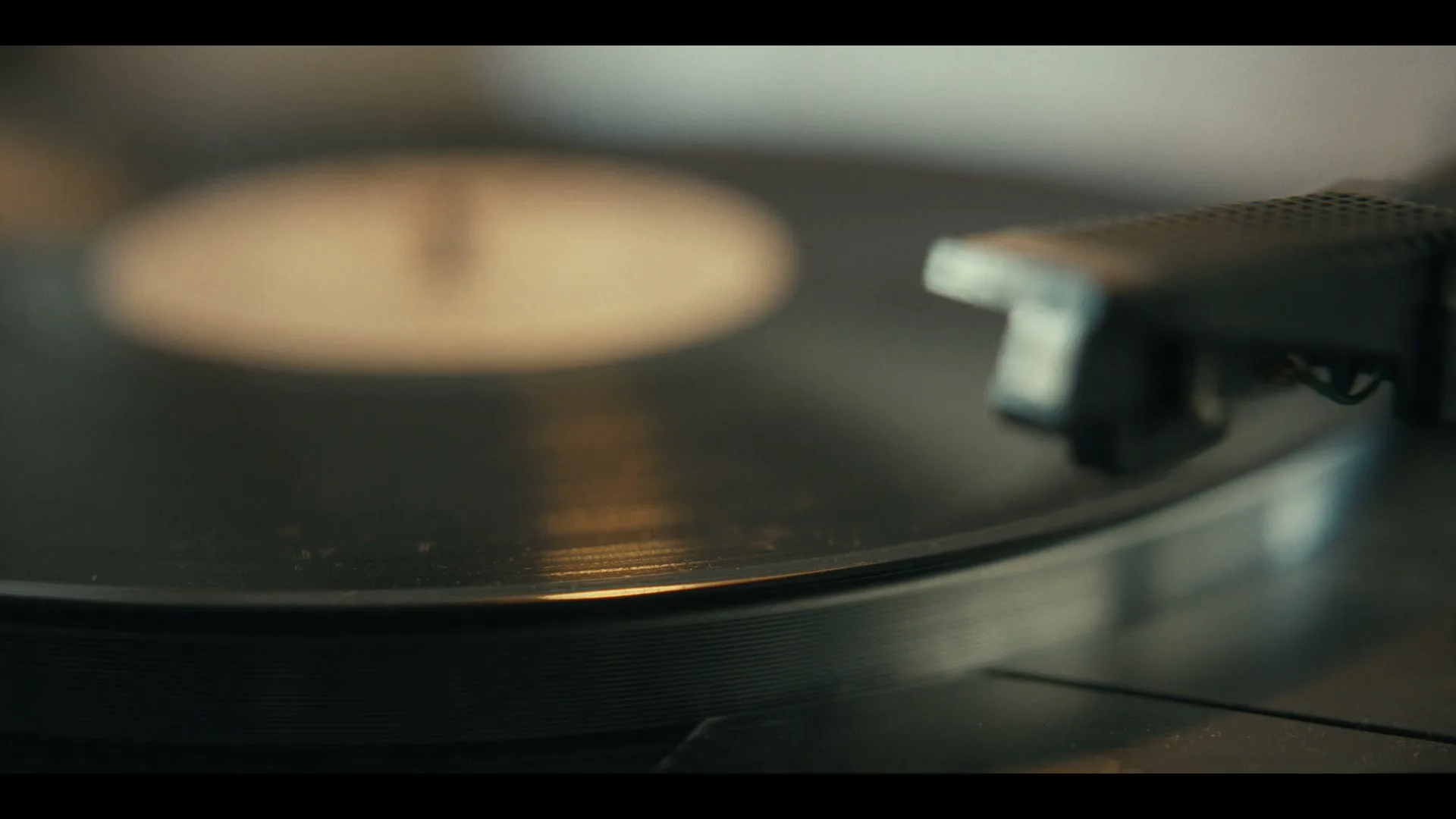 A close-up shot shows a hand placing a record player needle onto a spinning vinyl record, creating a nostalgic atmosphere.