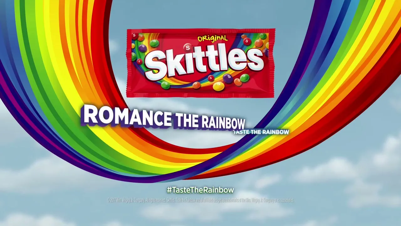 A Skittles candy bag and the tagline "ROMANCE THE RAINBOW TASTE THE RAINBOW" appear over a rainbow against a blue sky with clouds.