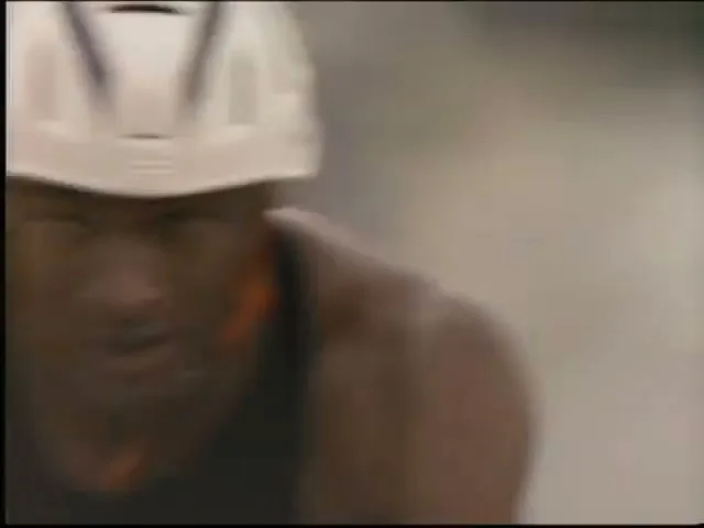 Bo Jackson, a male athlete, wears a white helmet and black cycling gear while riding a bicycle outdoors on a sunny day.